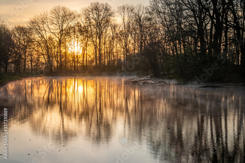 Atmospheric sunrise in the Netherlands with a beautiful orange glow in the air and water vapor over the fields and the canal and ponds