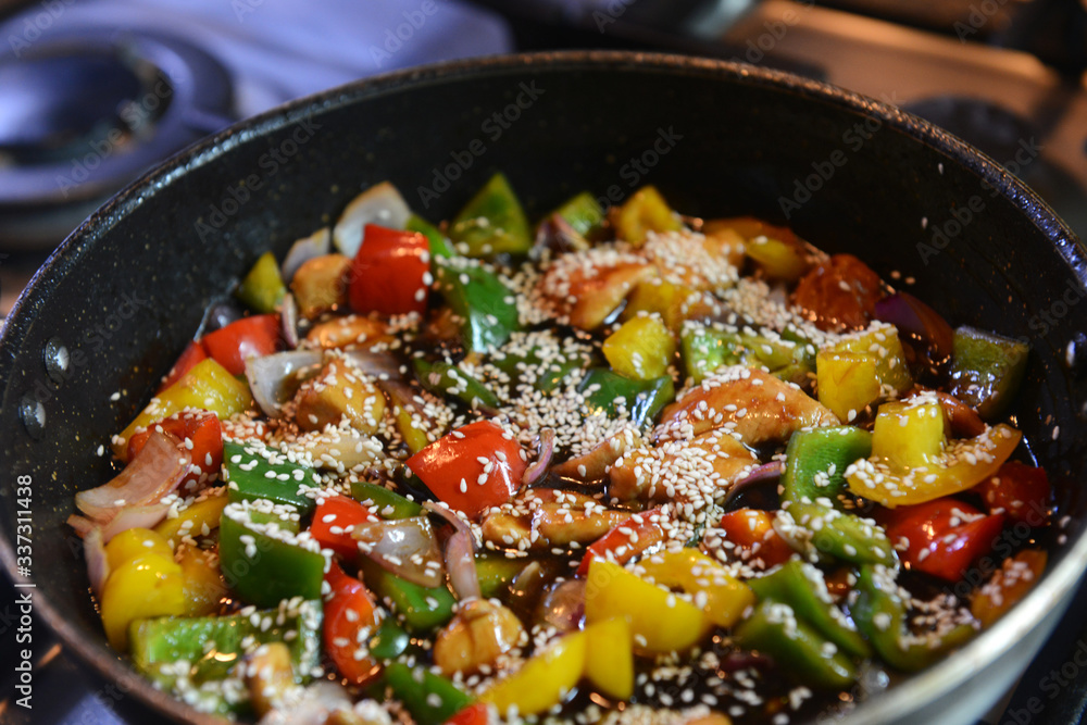 Freshly prepared stir fry with chicken and vegetables including onions, red, yellow and green capsicum in a wok Freshly prepared stir fry with chicken and vegetables including onions, red, yellow and green capsicum in a wok