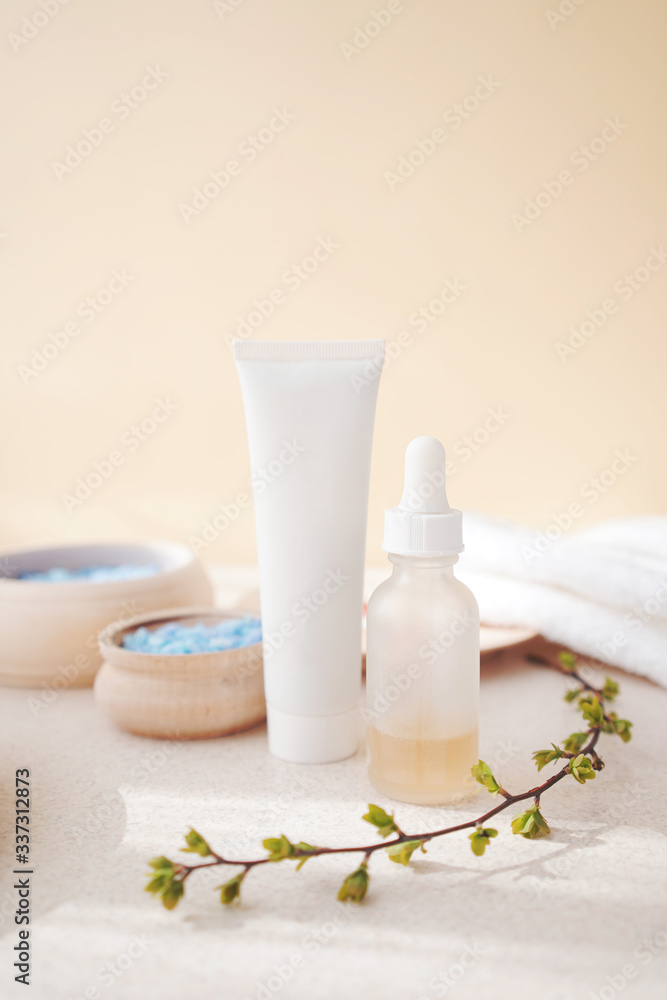 spa skin care - serum and tube with face cream on a background of bowls with different components