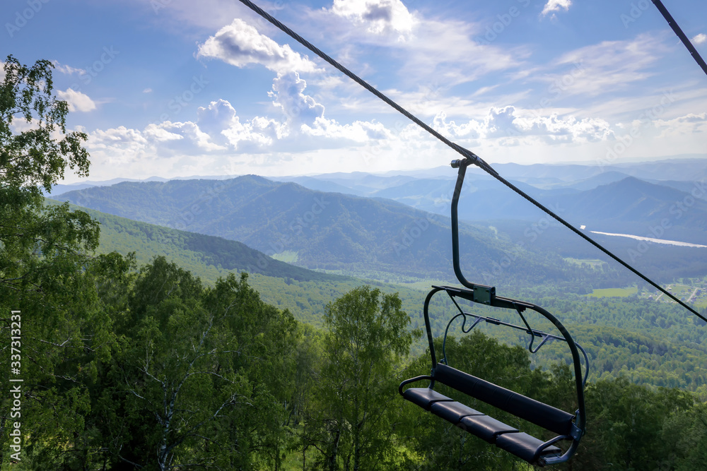 Lift on the background of mountains and green hills on sunny summer day. Empty bench of ski lift, tourism closed off quarantine. Inactive resorts. Lift on the background of mountains and green hills on sunny summer day. Empty bench of ski lift, tourism closed off quarantine. Inactive resorts.