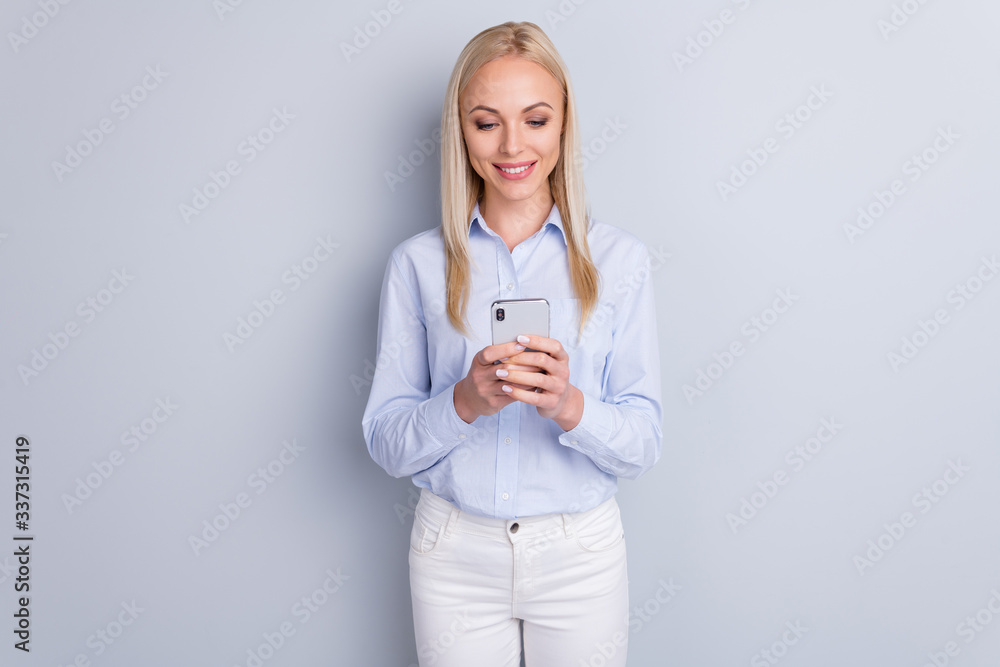 Portrait of positive cheerful girl use smartphone have online social network communication share subscribe read news wear good look trousers isolated over gray color background Portrait of positive cheerful girl use smartphone have online social network communication share subscribe read news wear good look trousers isolated over gray color background