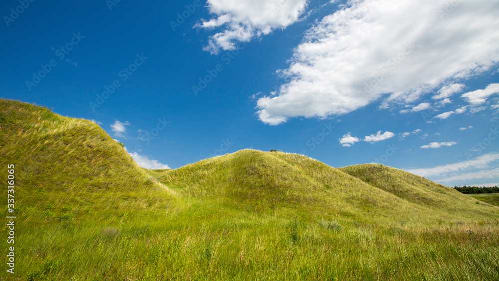 Naklejka premium grass-covered hills above the valley on a sunny day