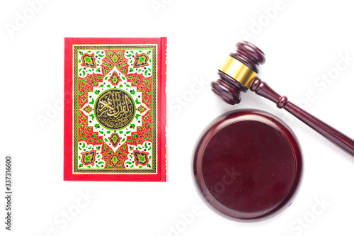 Flatlay picture of Quran with law gavel on white background for sharia or Islamic law concept. Large Arabic word mention the Holy Quran is with variance recitation and correct pronounciations method. photo