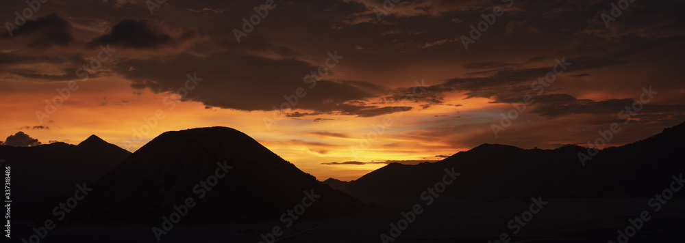 Stunning dramatic sunset behind the silhouette of the mountain range that includes Mount Semeru, Mount Batok and Mount Bromo in East Java, Indonesia.