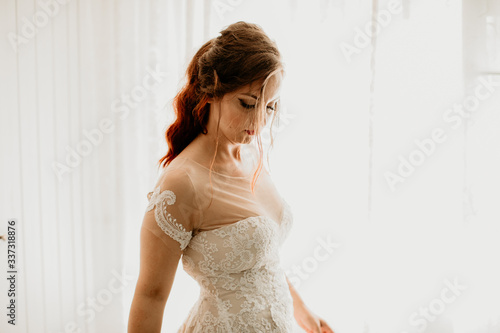 Happy bride posing in room near wedding dress