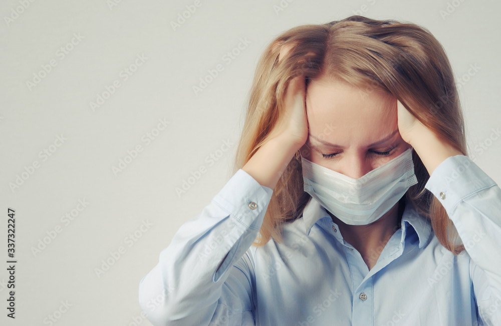 young woman holding her head, with a medical mask. pain, suffering and frustration concept young woman holding her head, with a medical mask. pain, suffering and frustration concept
