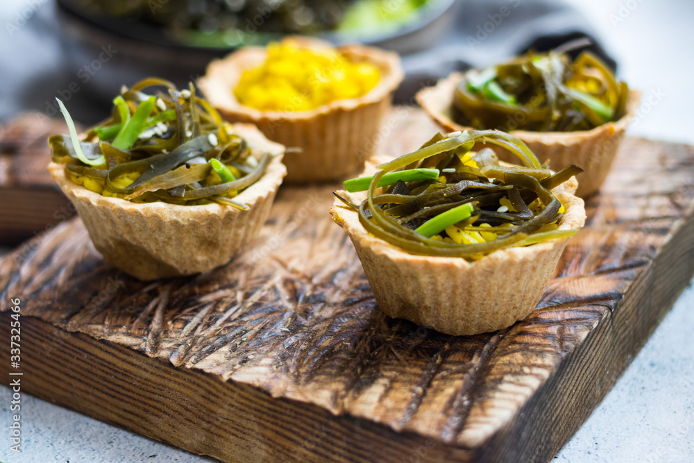 Vegan tarts with long rice filling and stuffed with laminaria kelp seaweed salad. Healthy snack.