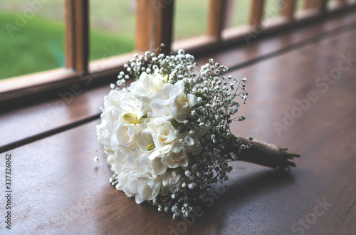A beautiful wedding bouquet of white roses and flowers next to a window