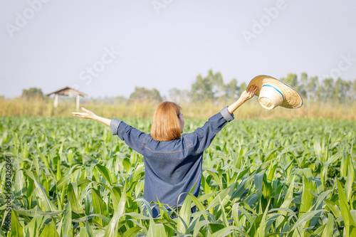 A womale farmer gesturing with raised hands at corn farm photo