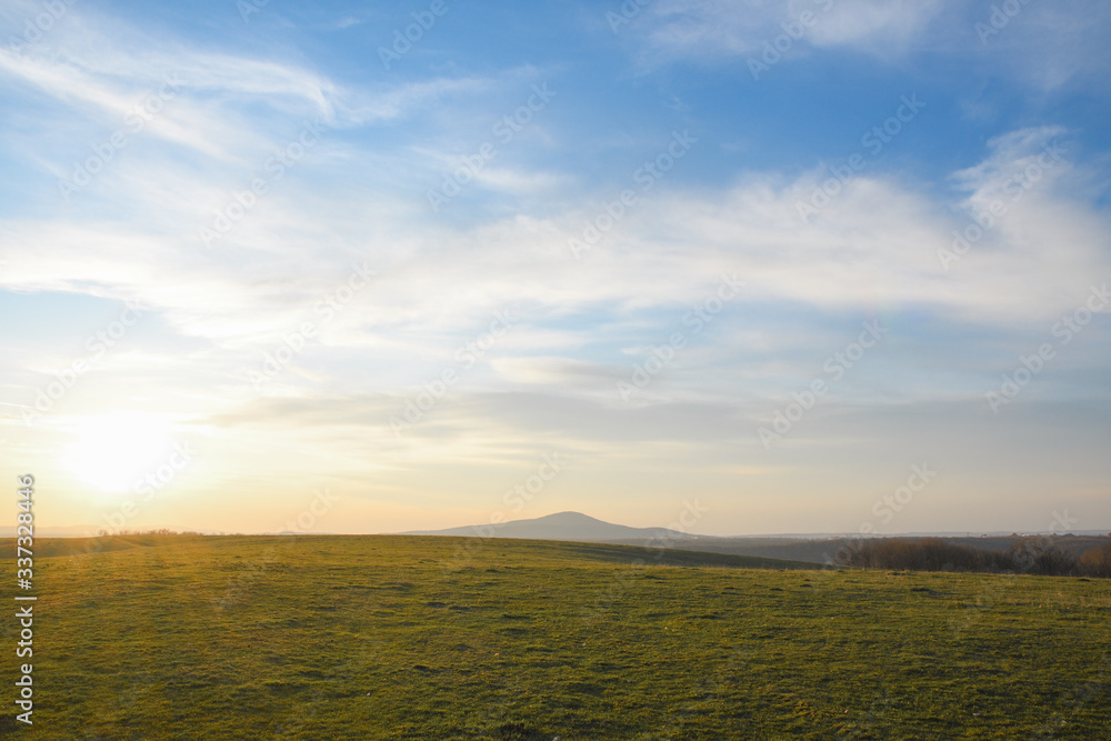 Landscape with green meadow and blue sky with clouds on sunset Landscape with green meadow and blue sky with clouds on sunset