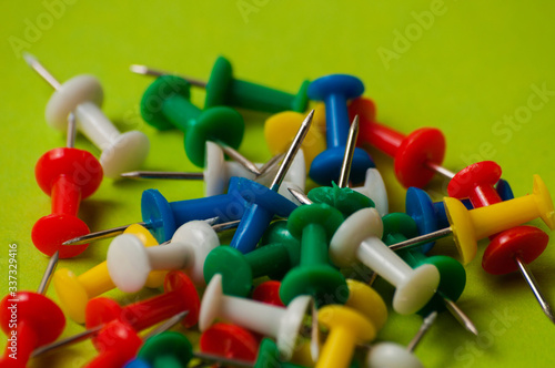 Many thumbtacks of different colors on green designer paper