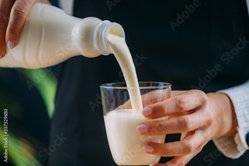 Pouring Kefir into glass, a healthy fermented dairy superfood drink, rich in natural probiotics Lacto and Bifido Bacterium photo