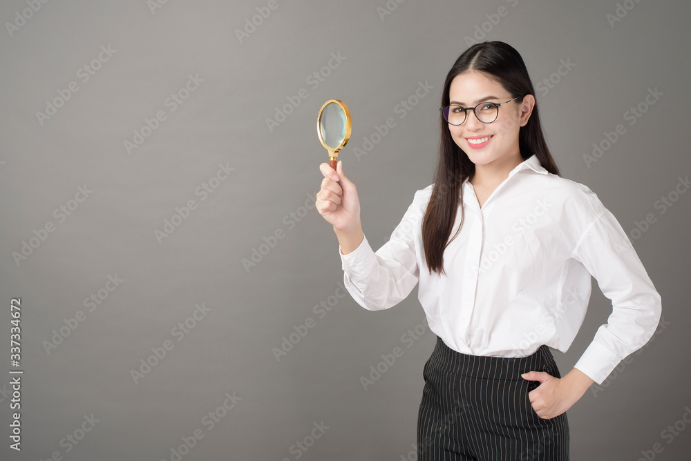 Beautiful woman is holding magnifying glass in studio Beautiful woman is holding magnifying glass in studio