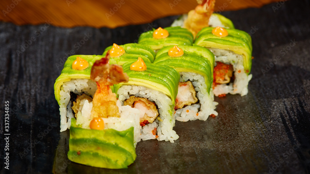 Big maki sushi. roll green dragon. Shallow dof. Photos | Adobe Stock