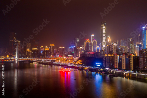 Aerial view of Hong Ya dong Cave, Historic Chinese folk religion town by Jialing River with lighted skyscrapers © Davidzfr