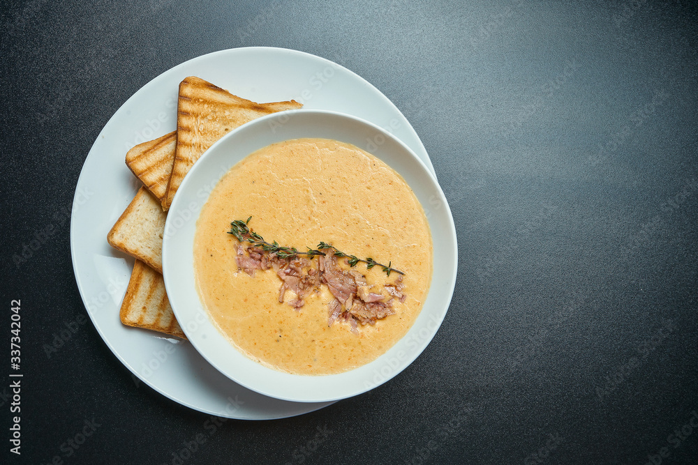 Tasty cheese cream soup with mushrooms and bacon, croutons in a white bowl isolated on a black background. Top view Tasty cheese cream soup with mushrooms and bacon, croutons in a white bowl isolated on a black background. Top view