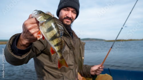 Fisherman holds perch and looks at the camera