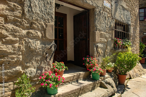 Masonry wall of a typical old Spanish house with a separate entrance to the apartments and steps with bright potted flowers