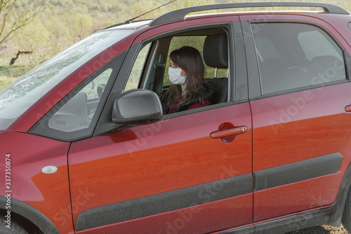 Girl in a medical mask and gloves in the car at the driver's seat