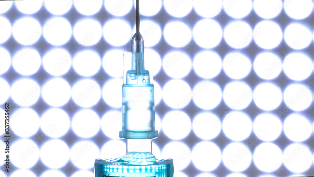A syringe for COVID-19 coronavirus vaccine inside the blue lighted room