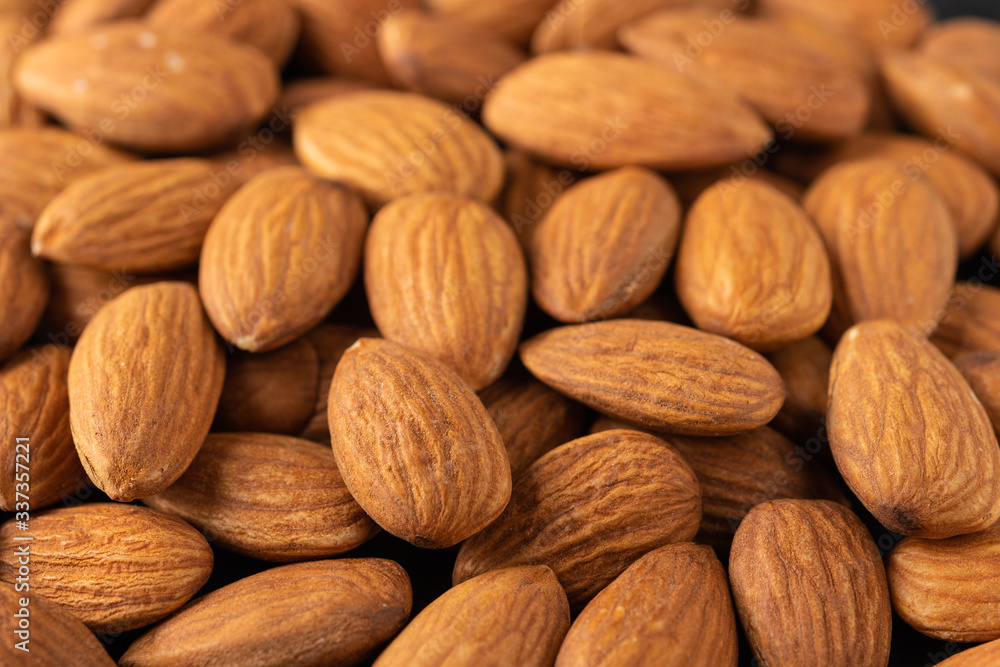 Background of large raw peeled almonds placed randomly. Close up. Food background Background of large raw peeled almonds placed randomly. Close up. Food background