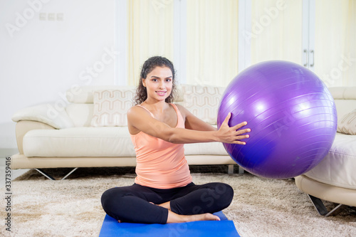 Indian woman doing yoga exercise with pilates ball