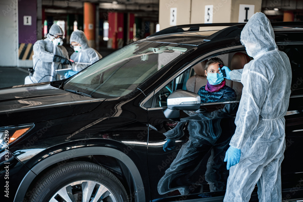 Medical worker measuring temperature of woman through car window before leaving quarantine zone. Stay at home Medical worker measuring temperature of woman through car window before leaving quarantine zone. Stay at home