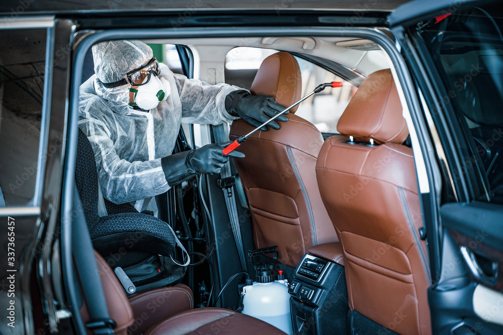 Disinfectant worker in protective mask and suit making disinfection of car seats - obrazy, fototapety, plakaty 