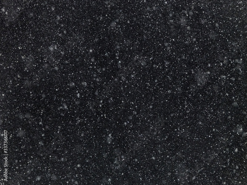 Texture of flakes of falling snow on a dark background.