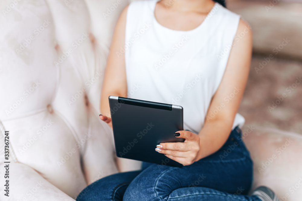 A young girl sits in chair with tablet and pays bills, online purchases, payment for goods during quarantine, A young girl undergoes online training, online training during quarantine A young girl sits in chair with tablet and pays bills, online purchases, payment for goods during quarantine, A young girl undergoes online training, online training during quarantine