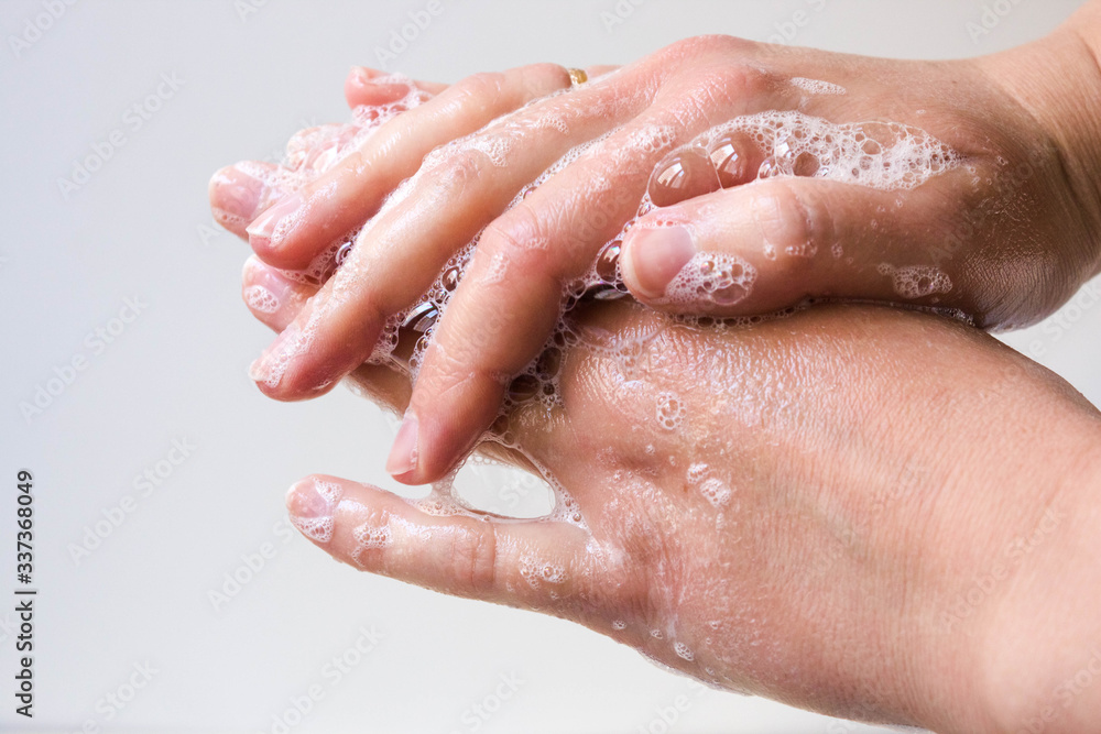 Hygiene and protection of hands from viruses (coronavirus) and bacteria using soap. Women's hands with foamed soap close-up on a white background. The process of properly washing hands with soap.