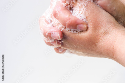 Hygiene and protection of hands from viruses  coronavirus  and bacteria using soap. The process of properly washing hands and fingers with soap foamed with water close-up on a white background
