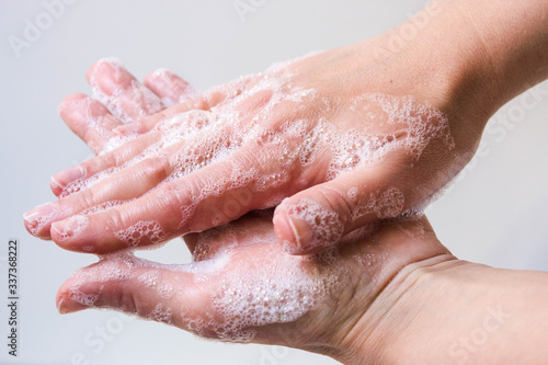 Hygiene and protection of hands from viruses (coronavirus) and bacteria using soap. Women's hands with foamed soap close-up on a white background. The process of properly washing hands with soap.