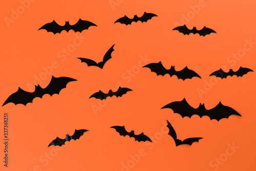 Halloween concept with many black horrible bats flying in a circle. Scary halloween flat lay composition on an orange background