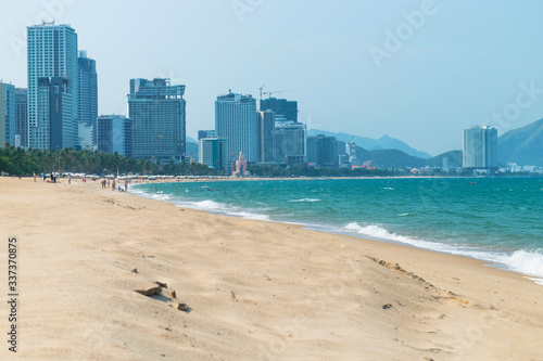 Empty sandy beach and sea waves with hotels on the beach on a sunny day