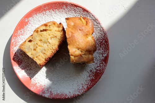 Freshly baked traditional apple charlotte pudding on a plate with powdered sugar. Light cake breakfast on white wooden background. Top view. Copy space