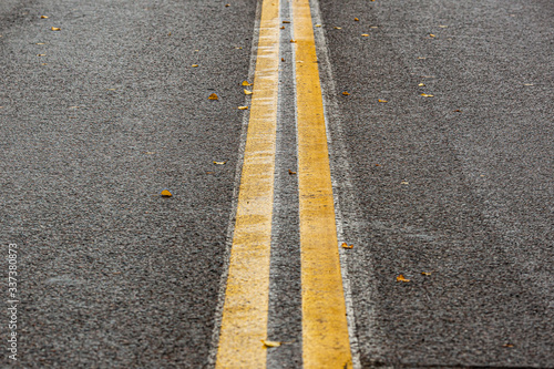 wet asphalt road with two yellow lanes