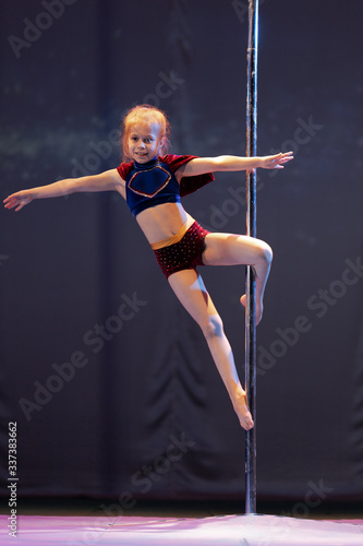 Girl athlete gymnast shows an acrobatic performance on a pylon. photo