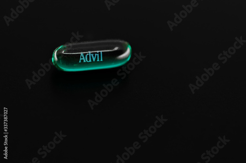UAE – Circa 2020: Green gel capsule of Advil Ibuprofen isolated on black background with copy space. Headache, migraine concept.