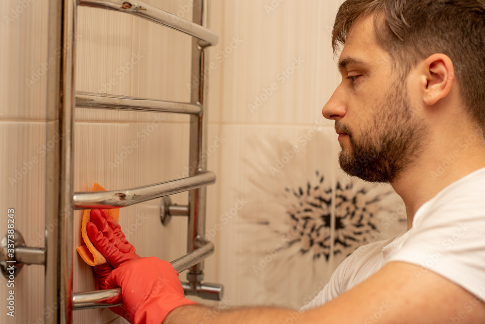 Close up photo of man doing housework, cleaning bathroom heater in orange gloves. Clean house, cleanliness, cleaning service concept