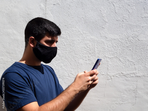 Young man with a black face mask using a mobile