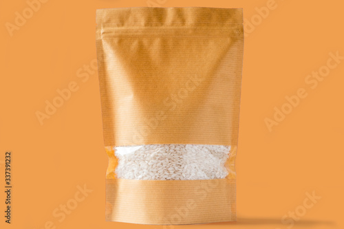 striped brown paper doypack stand up biodegradable pouch with window zipper on brown background filled with rice photo