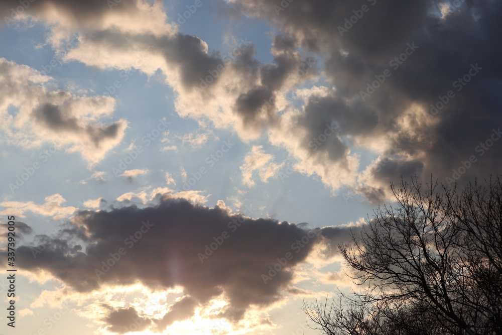 Morning sun shining up through patchy clouds with blue sky beyond Morning sun shining up through patchy clouds with blue sky beyond