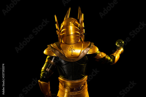 a male actor in a suit of an Egyptian mythology character, the golden deity Jackal Anubis, twists buugeng in yellow light on a black background photo