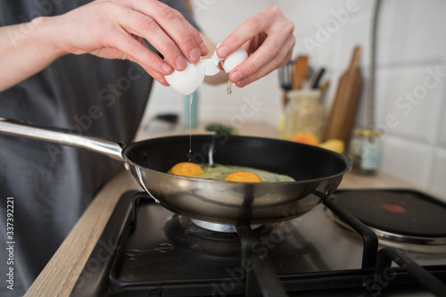 young girl prepares eggs in light kitchen, scandinavian style