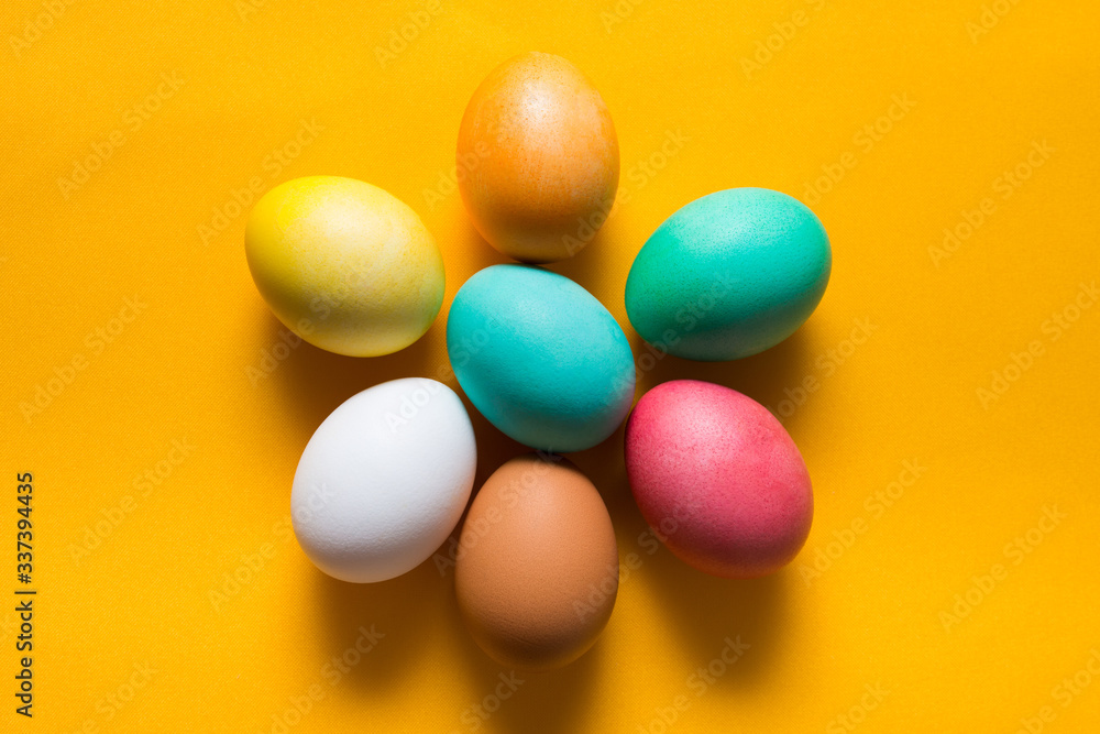 Colored easter eggs on a yellow background from above