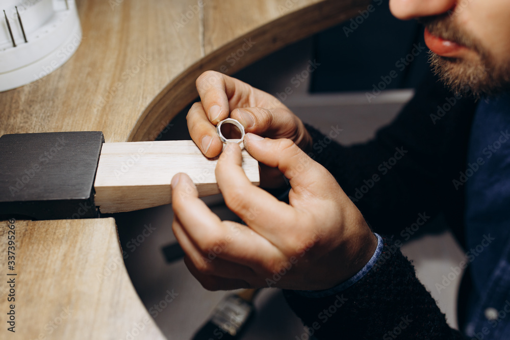 Fototapeta premium Man hands close up making silver jewelry top view preparation process dark. Working tools on the table. Handicraft people art concept. He makes silver ring