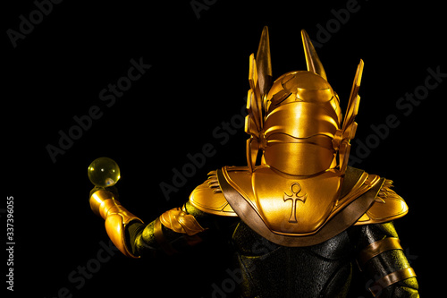 a male actor in a suit of an Egyptian mythology character, the golden deity Jackal Anubis, twists buugeng in yellow light on a black background photo