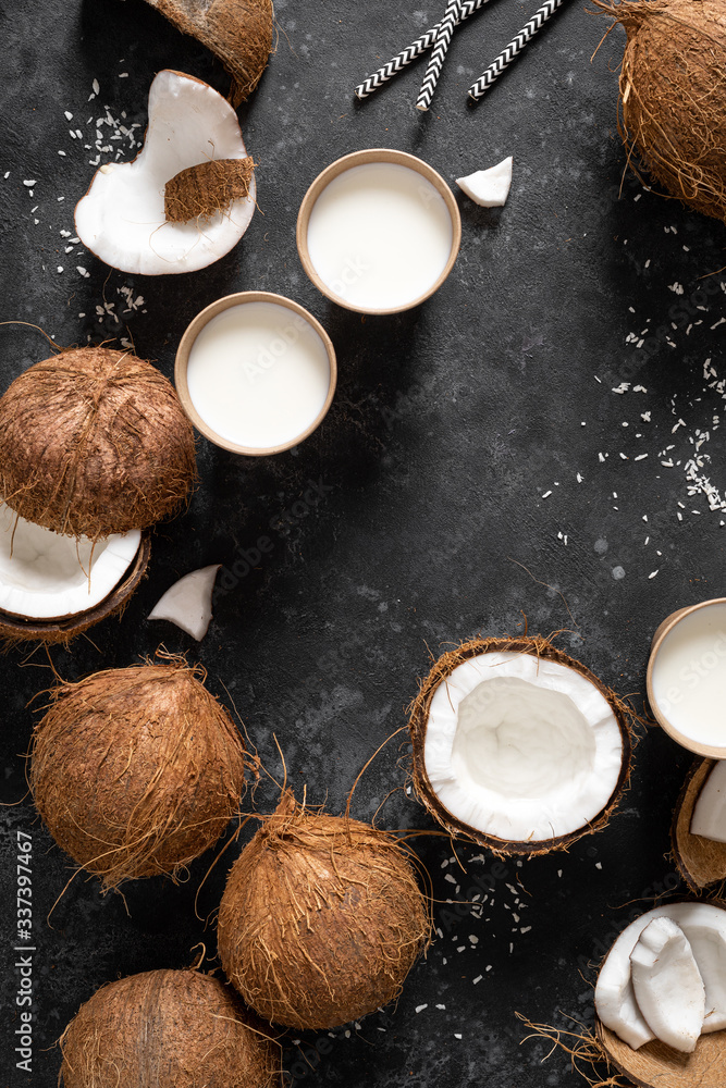 Coconut milk, whole and cracked coconuts on black background, top view Coconut milk, whole and cracked coconuts on black background, top view