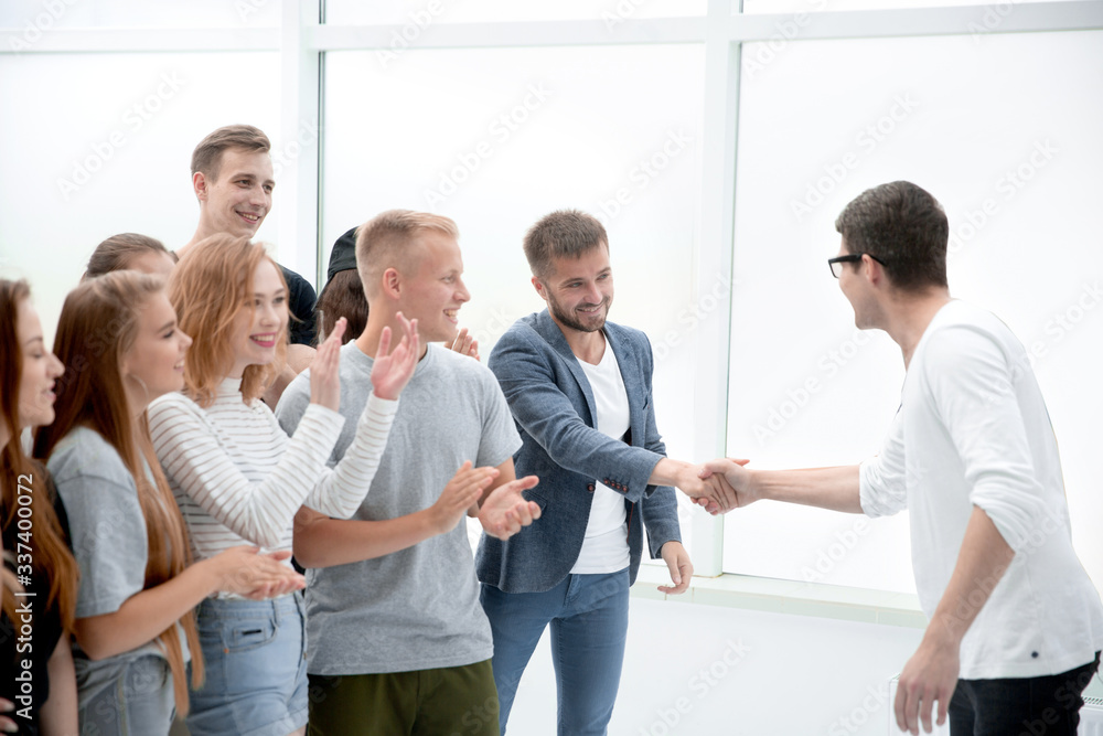 young people shaking hands, standing among their friends young people shaking hands, standing among their friends